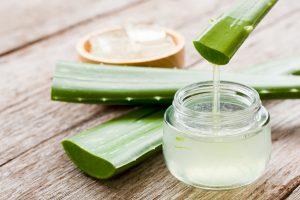 Aus einem Aloe-Vera-Blatt tropft Gel in ein kleines Glas.