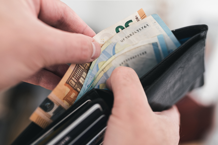 Hände nehmen Euro-Geldscheine aus einem Portemonnaie als Symbol für bewusstes Sparen beim Einkauf im Supermarkt.